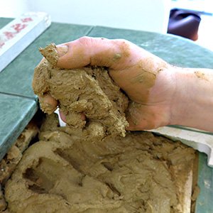 Hafnerhand beim Ofenbau mit Lehm